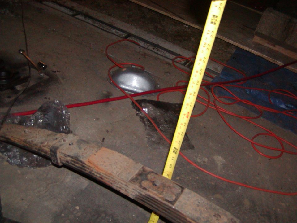Leaf spring with yellow measuring tape showing approximately 12 inches