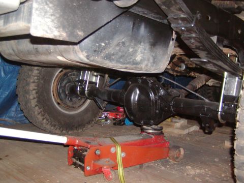 1991 Ford Bronco - Undercarriage view of a vehicle's rear axle and suspension system, with a hydraulic jack providing support.