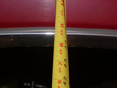 1991 Ford Bronco - A close-up of a red vehicle's body and chrome trim is shown with a measuring tape indicating dimensions.