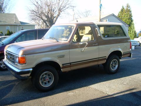 1992 Ford Bronco - This two-tone brown and tan Ford Bronco is seen from a 3/4 front angle. A sticker on the windshield indicates the year '89.