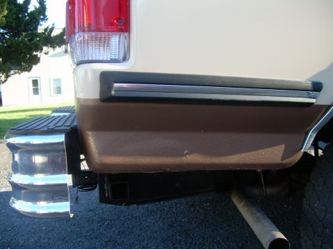 1992 Ford Bronco - Close-up of the rear corner of a vehicle, showing the taillight, two-tone paint, and bumper details.