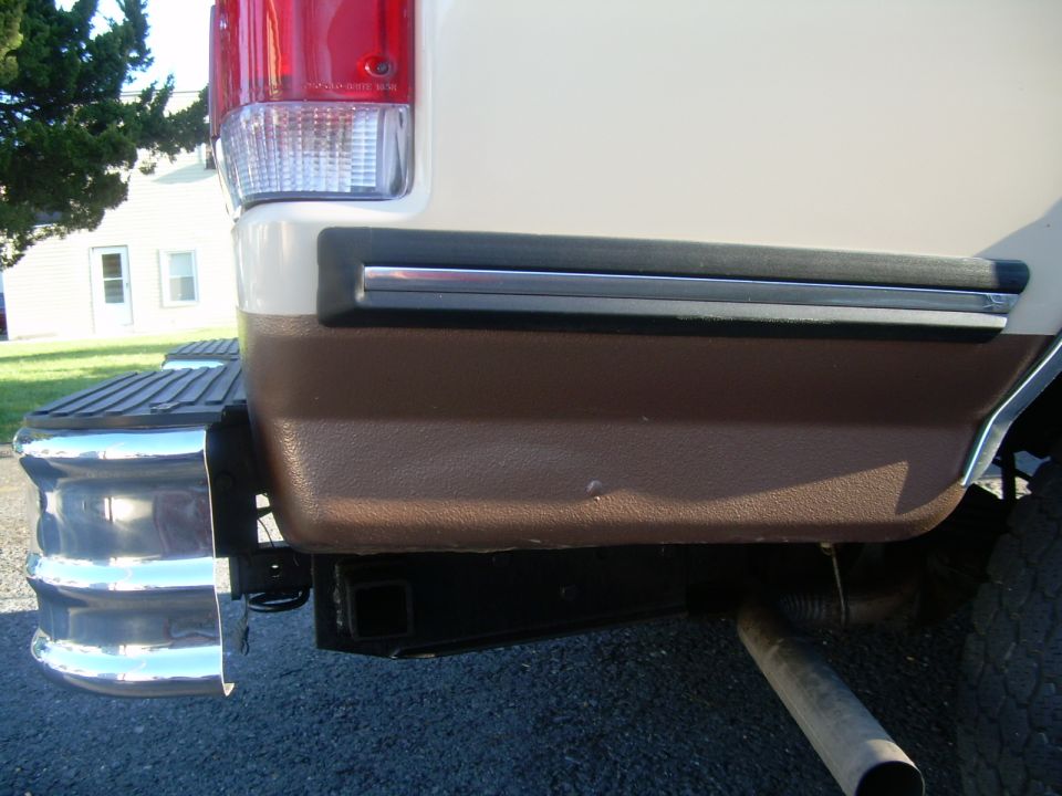 Rear of a two-tone SUV with chrome bumper steps and a trailer hitch receiver