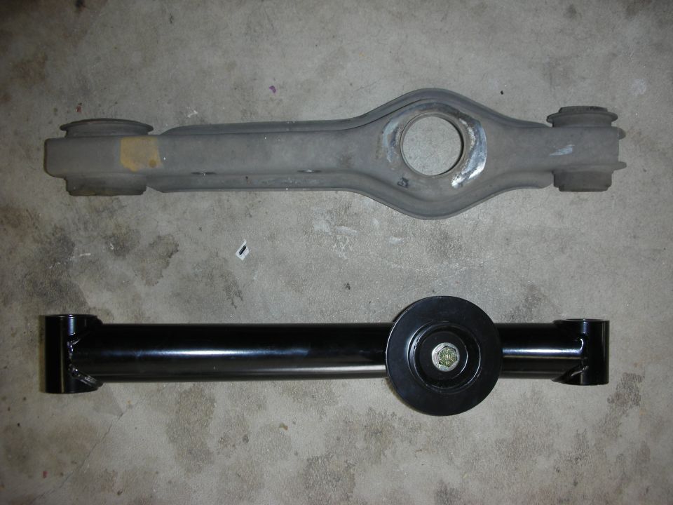 Old gray control arm above new black control arm with a circular mount