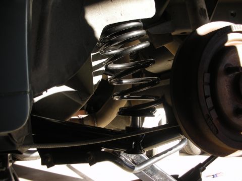 1990 Ford Mustang - Close-up of a vehicle's rear suspension system, focusing on the coil spring and brake drum.
