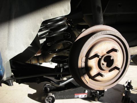 1990 Ford Mustang - Close-up of a vehicle's rear suspension system, showing a brake drum and coil spring.