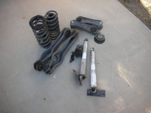 1990 Ford Mustang - Various suspension components laid out on a concrete surface, including springs, control arms, and shock absorbers.