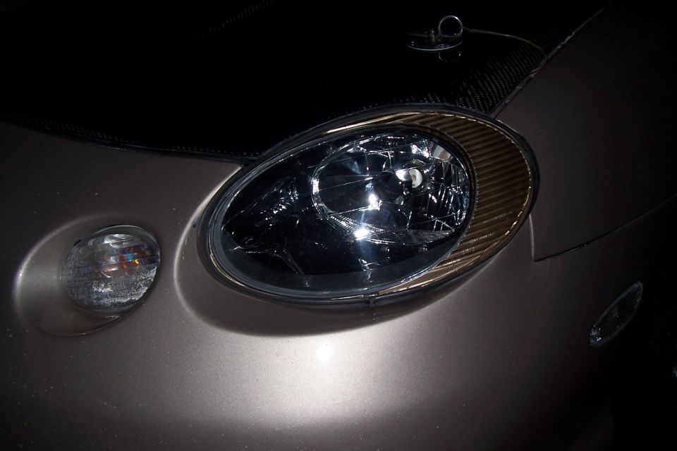 Close-up of blacked-out oval headlight and round turn signal on a gold sedan