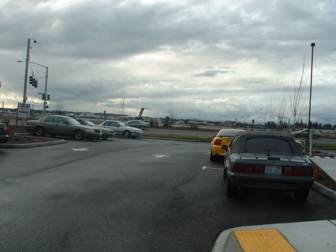 2000 Ford Crown Victoria - Several cars are parked in a lot under a cloudy sky, with a small airplane visible in the distance.