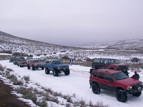 2003 Ford Ranger - Several modified trucks and SUVs drive in a convoy through a snow-covered landscape.