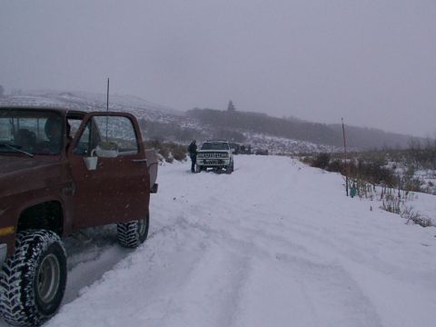 2003 Ford Ranger - Multiple vehicles navigate a snowy path during a winter outing, with a brown truck in the foreground and a white SUV further down the road.