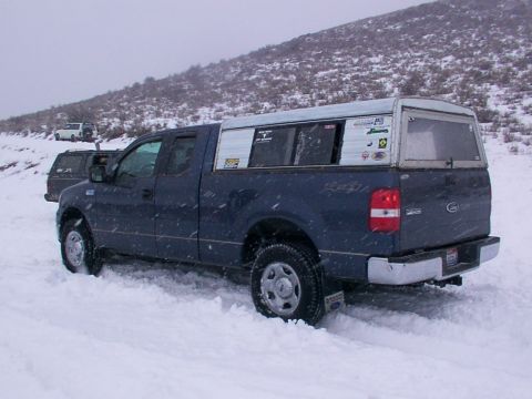 2003 Ford Ranger - Two trucks driving in the snow on a hillside, one with a white camper shell.
