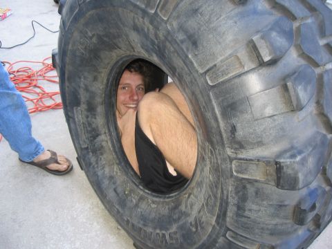 1974 Ford F-100 - A person is humorously posing inside a very large tire.