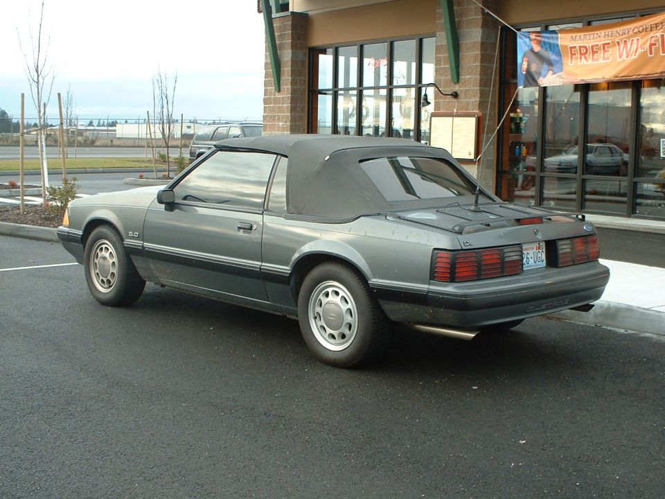 Gray 1987 Ford Mustang convertible with a black soft top parked in a lot