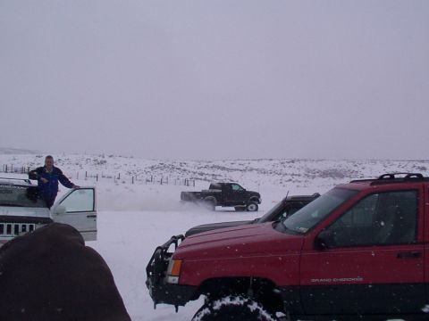 2003 Ford Ranger - Several off-road vehicles are seen in a snowy landscape with a person standing by one of them.