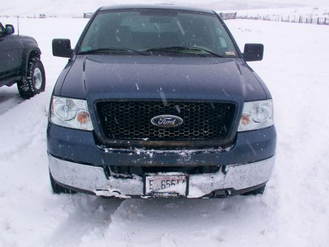 2003 Ford Ranger - A dark blue Ford F-150 truck is parked in the snow, showing its front grille and bumper.