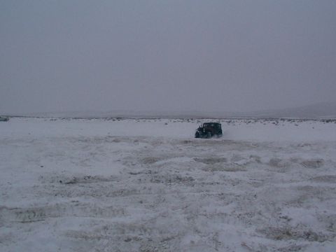 2003 Ford Ranger - A dark SUV navigates a snow-covered landscape under an overcast sky.
