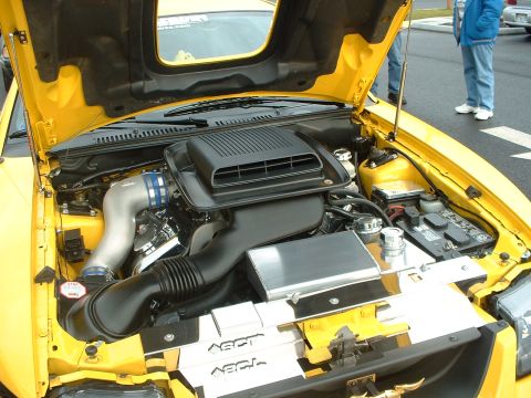 2000 Ford Crown Victoria - The engine bay of a yellow car is open, revealing custom modifications and the engine components.