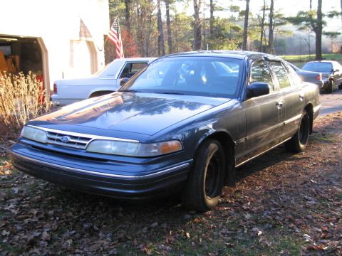 1991 Ford LTD Crown Victoria - A 1991 Ford Crown Victoria is parked in front of a garage with an American flag visible.