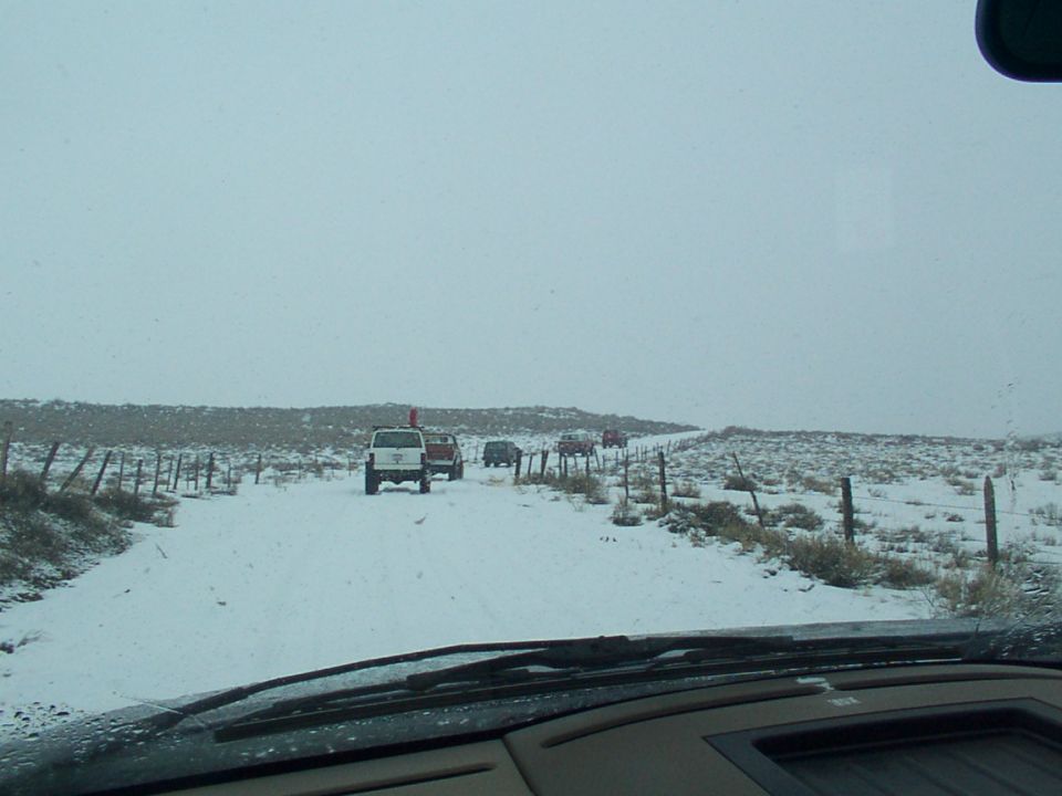 Multiple SUVs driving on a snow-covered road in a rural area