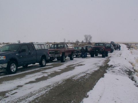 2003 Ford Ranger - A convoy of trucks drives down a snow-covered road under a cloudy sky.