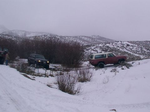 2003 Ford Ranger - Two SUVs navigate a snow-covered rural landscape with hills in the background.