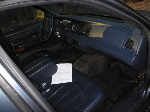 1991 Ford LTD Crown Victoria - The interior of a 1991 Ford Crown Victoria LTD is visible, dark upholstery and a document on the passenger seat.