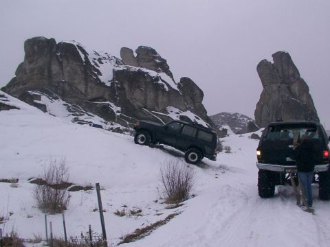 2003 Ford Ranger - Two SUVs navigate a snowy incline with distinctive rock formations in the background.