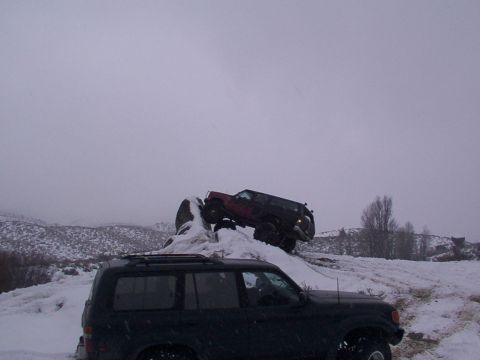 2003 Ford Ranger - Two SUVs navigate a snowy terrain, one climbing a rock formation.