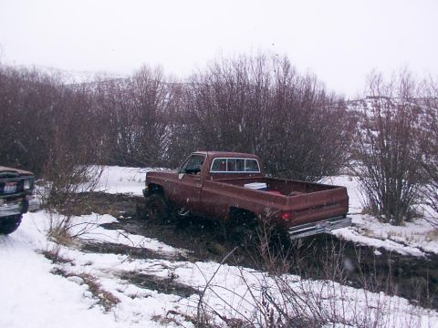 2003 Ford Ranger - A brown pickup truck is stuck in a muddy, snowy area with trees in the background.