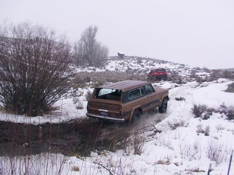 2003 Ford Ranger - A brown SUV navigates a muddy, snowy trail with a red SUV following in the distance.