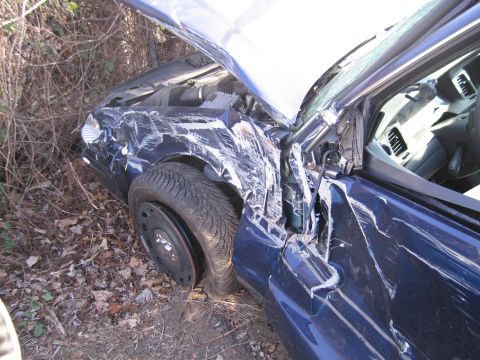 1991 Ford LTD Crown Victoria - This severely damaged blue sedan is off the road, with its hood and door ajar.