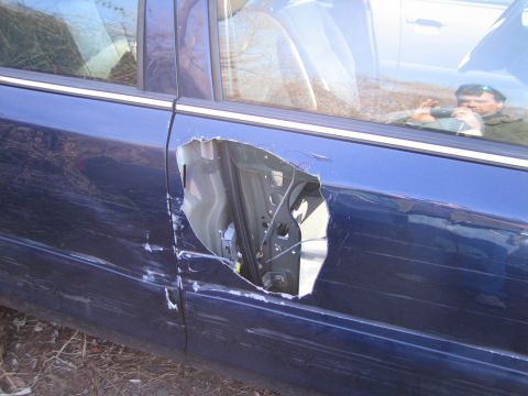1991 Ford LTD Crown Victoria - A damaged blue sedan door reveals its internal components, with visible dents and scratches on the exterior.
