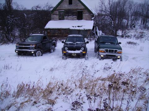 2000 Chevrolet Tahoe - Three trucks and SUVs are parked in a snowy field with an abandoned barn in the background.