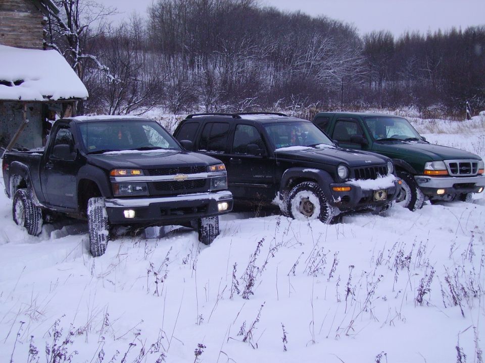 Black Chevrolet Colorado pickup, black Jeep Liberty, and green Ford Ranger parked in snow