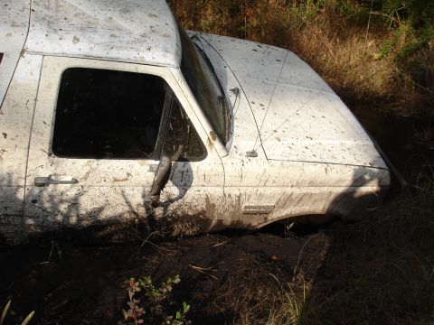 1989 Ford Bronco - This white 1989 Ford Bronco appears to be stuck deep in the mud, with only its front portion visible.