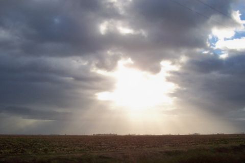 1994 Ford F-150 - Sunbeams pierce through dark clouds over a desolate field, hinting at a storm's end.