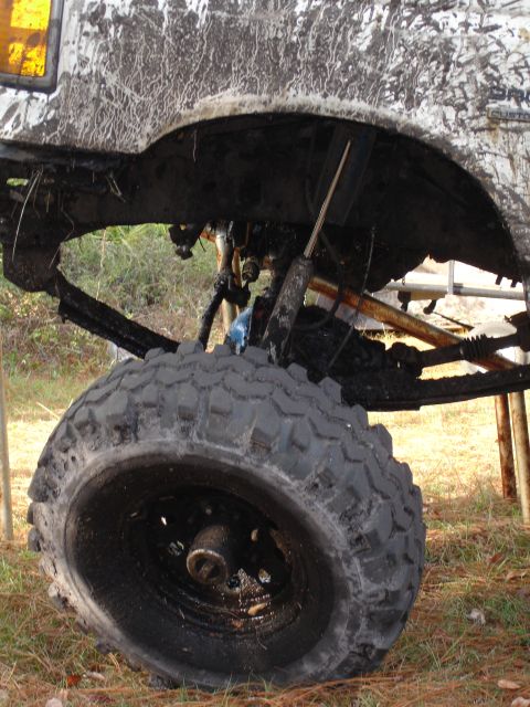 1989 Ford Bronco - Close-up view of the heavily soiled wheel and undercarriage of an off-road vehicle.