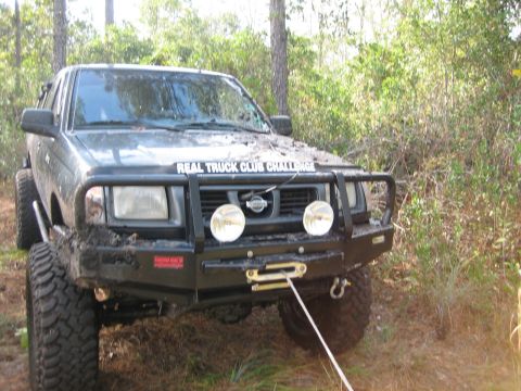 1989 Ford Bronco - A modified black Nissan pickup truck is shown in a wooded area, equipped for off-road challenges.
