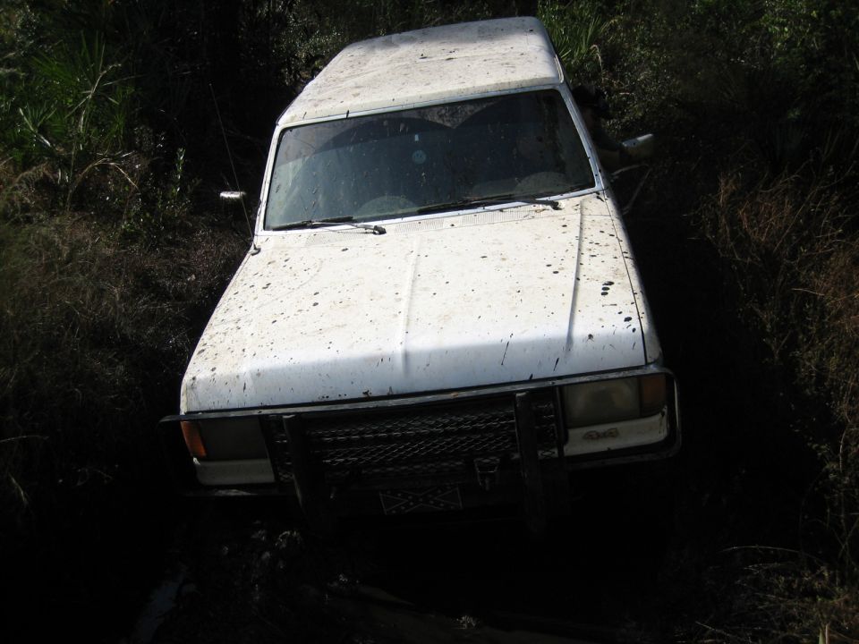 1989 Ford Bronco front view, stuck in mud and vegetation