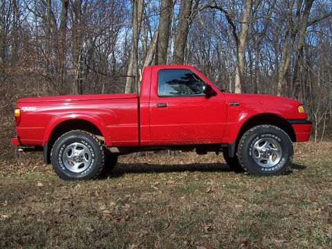 2001 Mazda B3000 - A red 2001 Mazda B3000 pickup truck is shown from the side in a natural setting with trees in the background.
