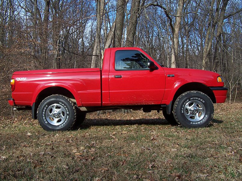 Red 2001 Mazda B3000 pickup truck parked in a wooded area