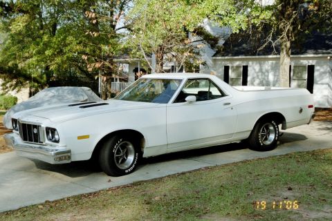 1976 Ford Ranchero - A white 1977 Ford Ranchero is parked in front of a house, with a tarp-covered vehicle behind it.