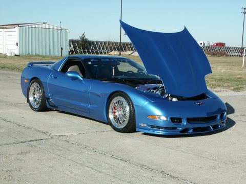 2001 Mercury Grand Marquis - A blue Chevrolet Corvette is parked outdoors with its hood raised, revealing the engine compartment.