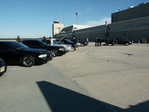 2001 Mercury Grand Marquis - Several black sedans, including a 2001 Mercury Grand Marquis, are parked in an airport lot on a sunny day.