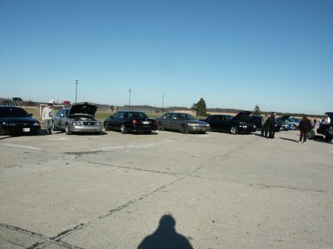 2001 Mercury Grand Marquis - A gathering of sedans, some with hoods open, parked in an open lot on a sunny day.