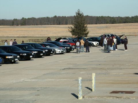 2001 Mercury Grand Marquis - Cars and people gathered outdoors on a sunny day, with a line of sedans in the foreground.