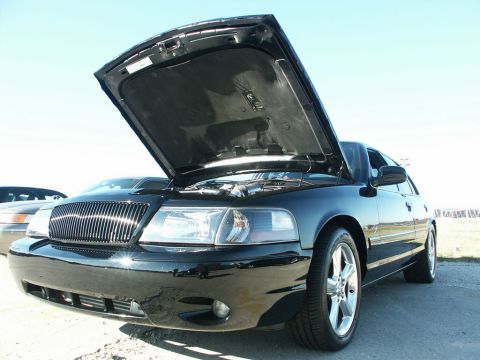 2001 Mercury Grand Marquis - A black 2001 Mercury Grand Marquis is shown with its hood open, revealing the engine bay. Another vehicle is partially visible in the backg…