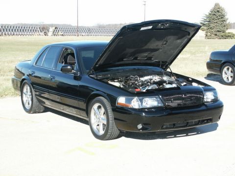 2001 Mercury Grand Marquis - Black 2001 Mercury Grand Marquis parked outdoors with its hood open, revealing the engine bay.