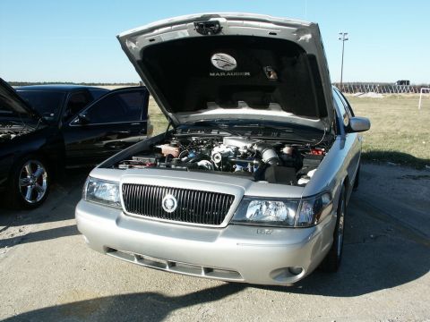 2001 Mercury Grand Marquis - A silver Mercury Marauder is parked with its hood open, revealing the engine compartment. Another car is parked nearby.