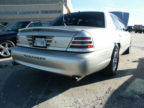 2001 Mercury Grand Marquis - A silver sedan with its hood up is parked next to another car, with 'Marauder' visible on its rear.